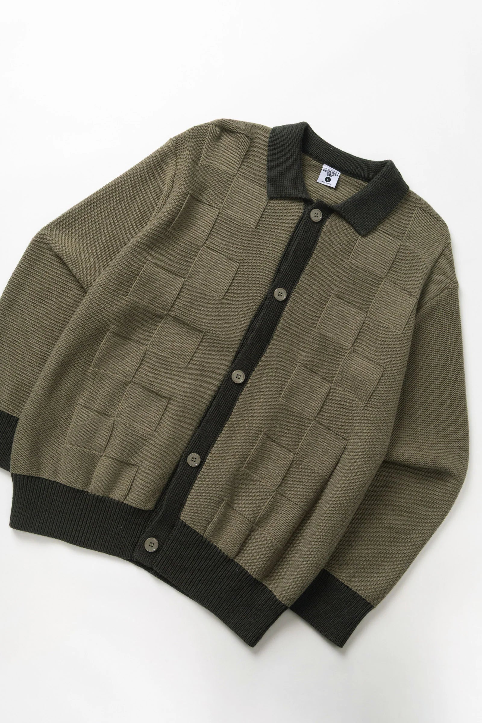 Green cardigan with black trim on a white background