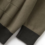 Close-up of a brown knitted sweater with black cuffs on a white background