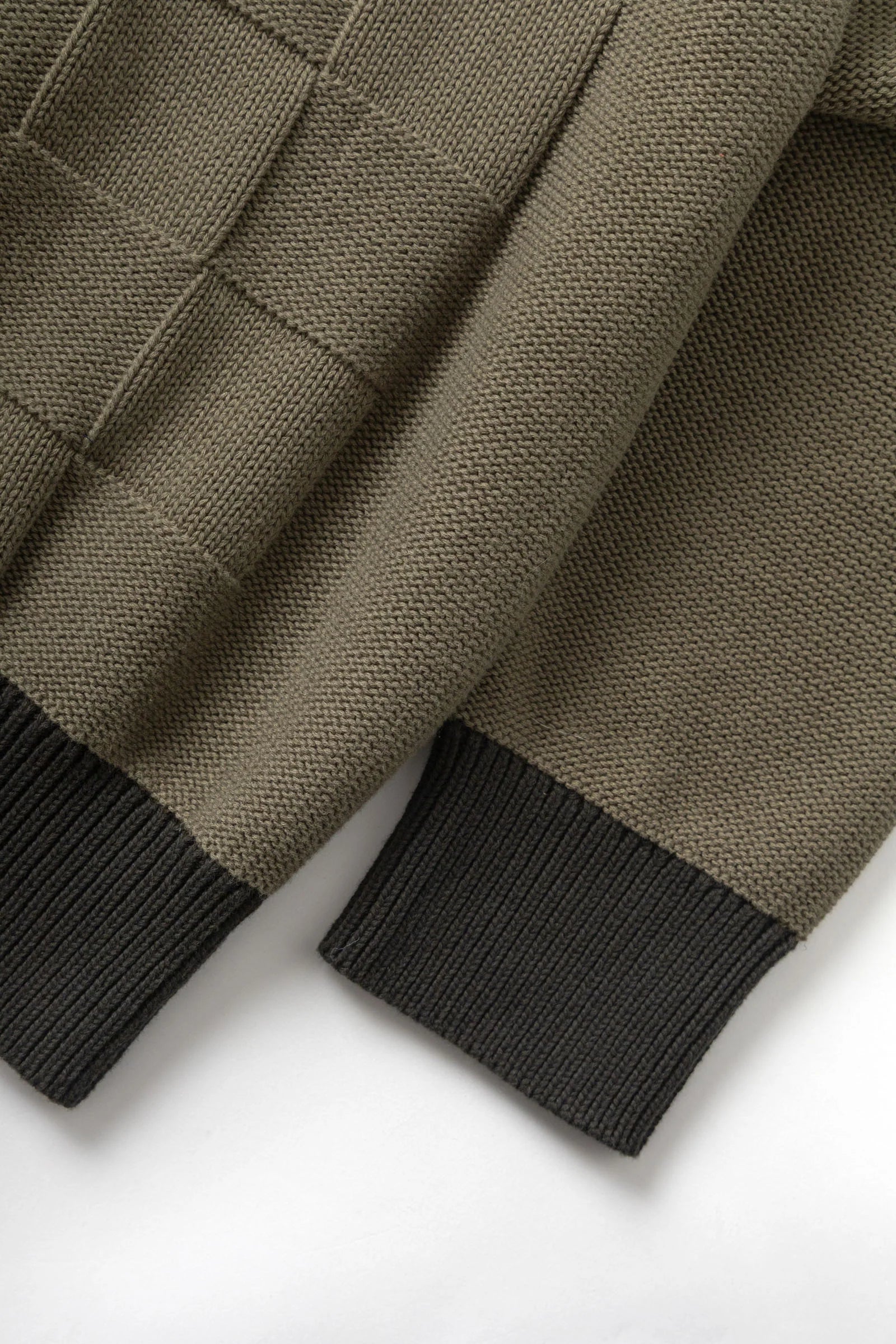 Close-up of a brown knitted sweater with black cuffs on a white background