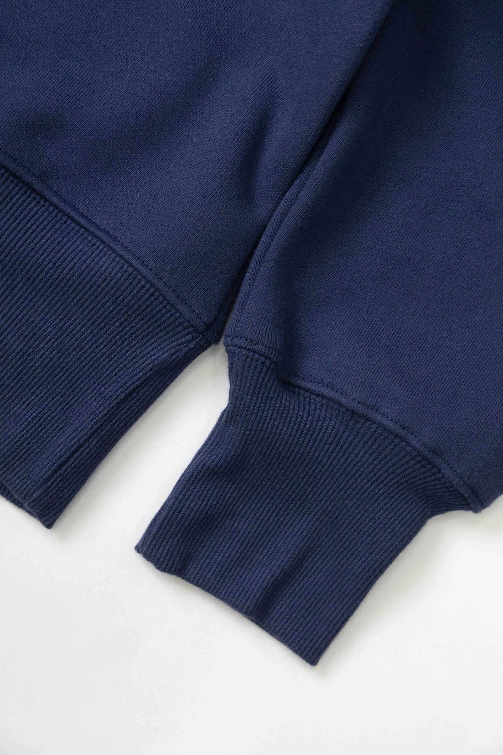 Close-up of a navy blue sweater sleeve on a white background