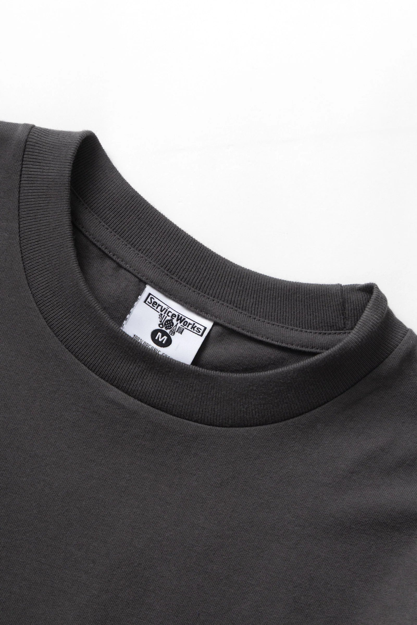 Close-up of a dark gray t-shirt with a brand label on a white background