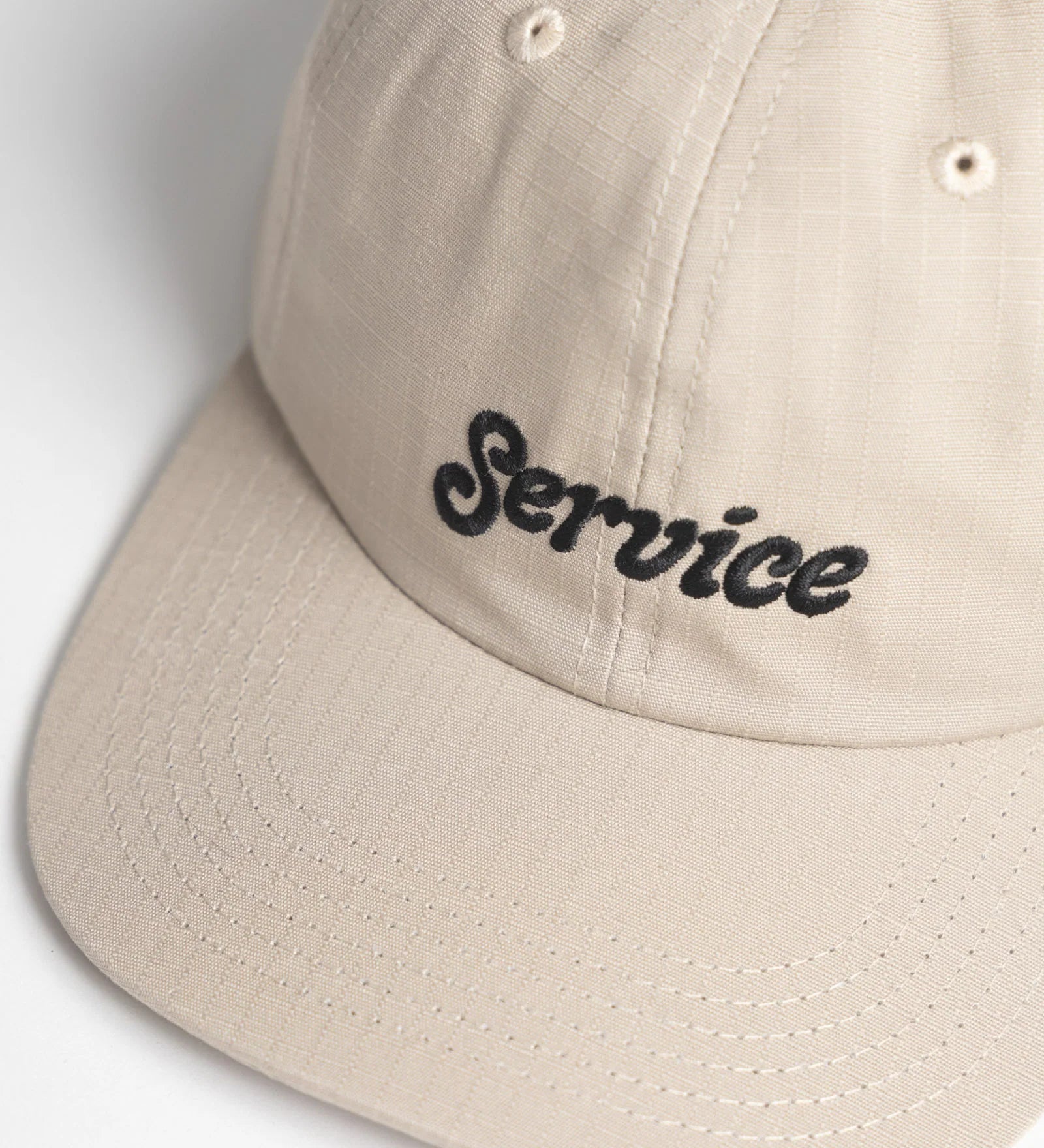 Beige cap with 'Service' embroidered on a light gray background