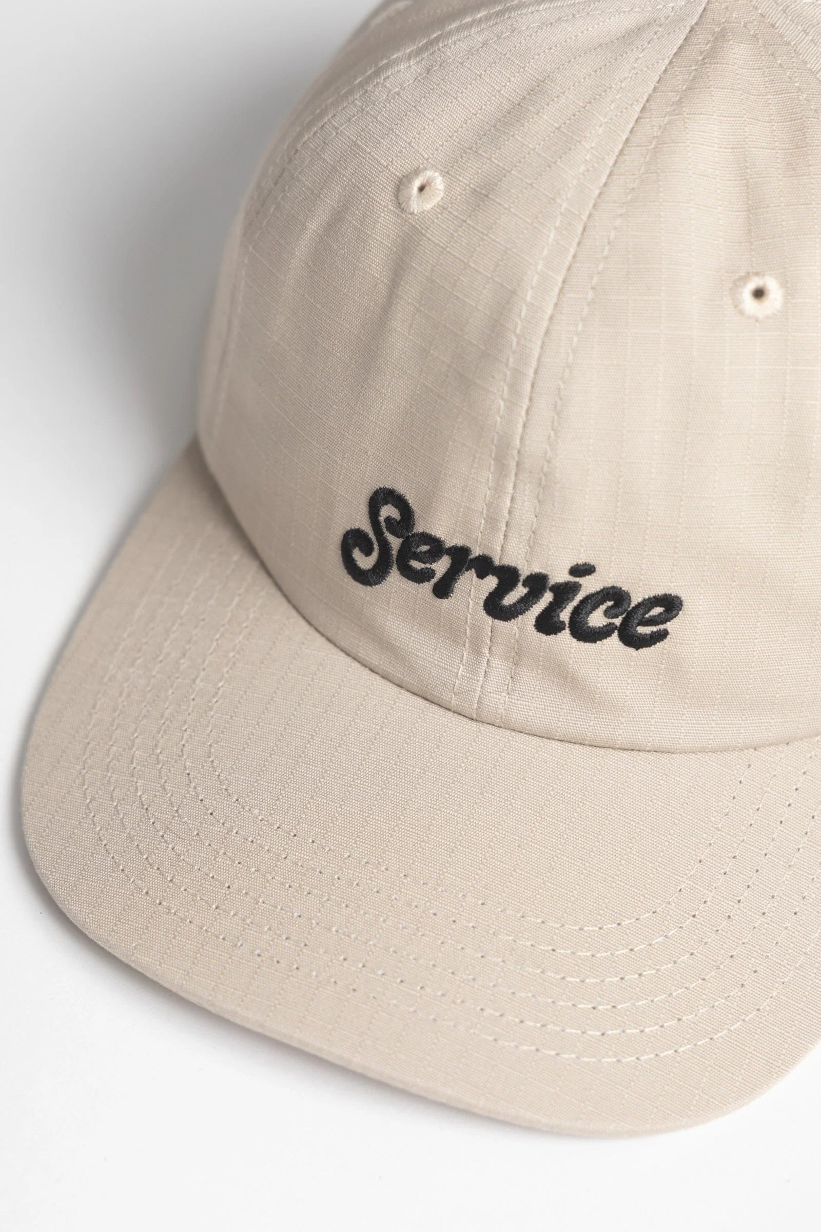 Beige cap with 'Service' embroidered on a light gray background