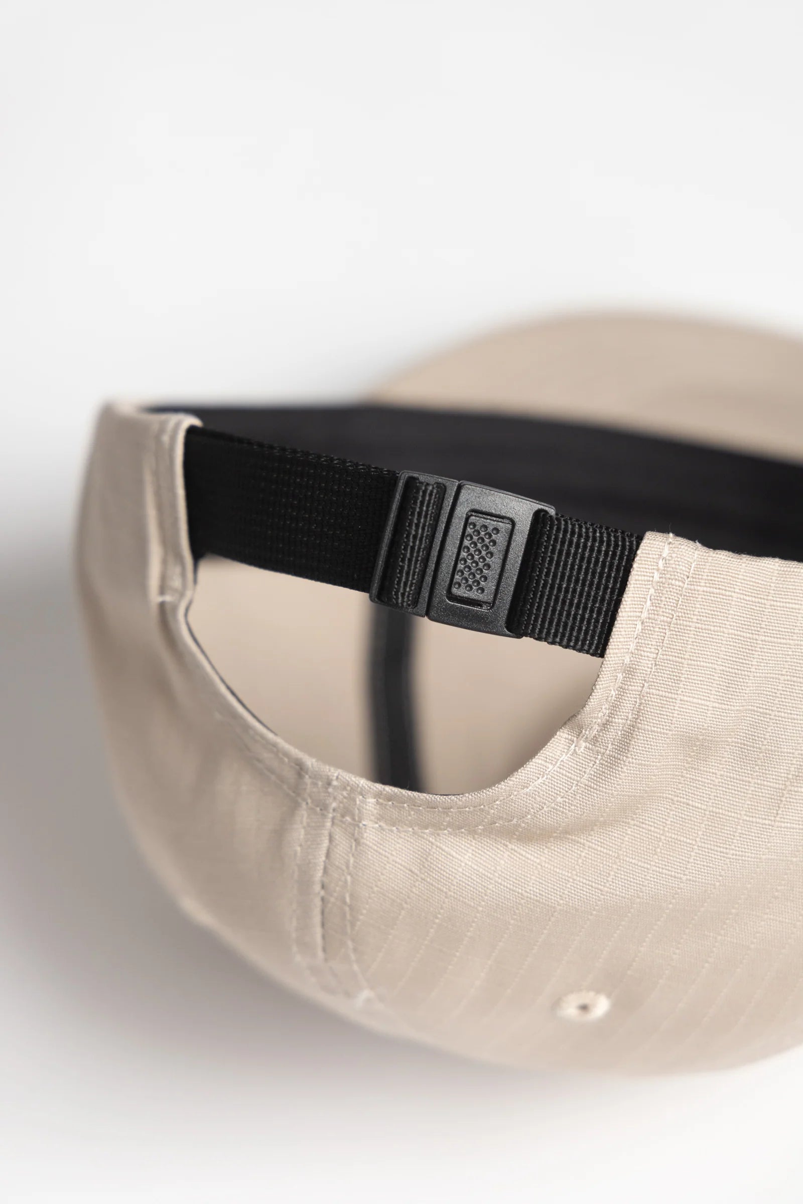 Beige cap with a black strap on a white background