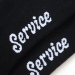Black socks with 'Service' embroidered in white on a white background