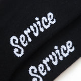 Black socks with 'Service' embroidered in white on a white background