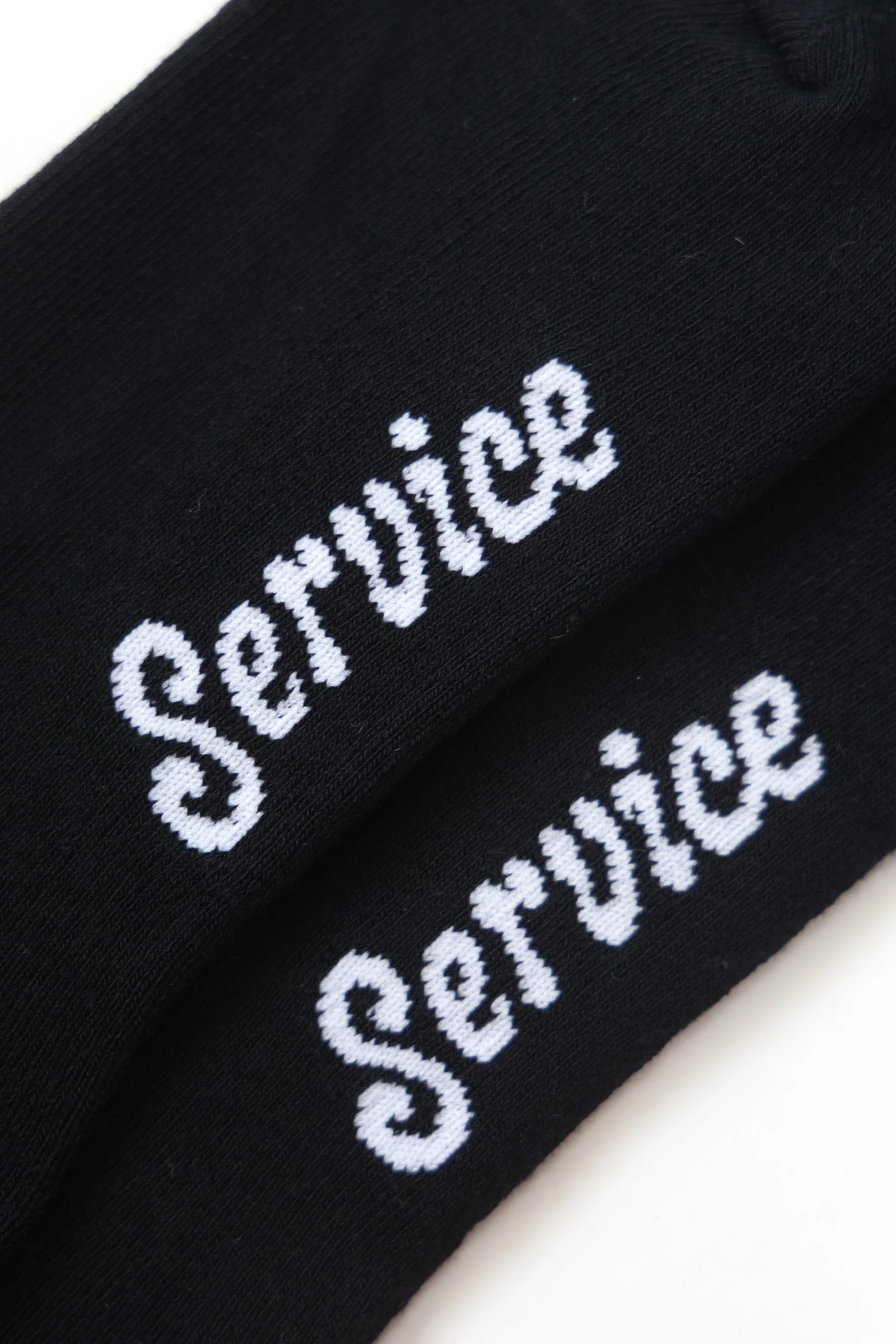 Black socks with 'Service' embroidered in white on a white background