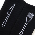 Black socks with white cutlery designs on a white background