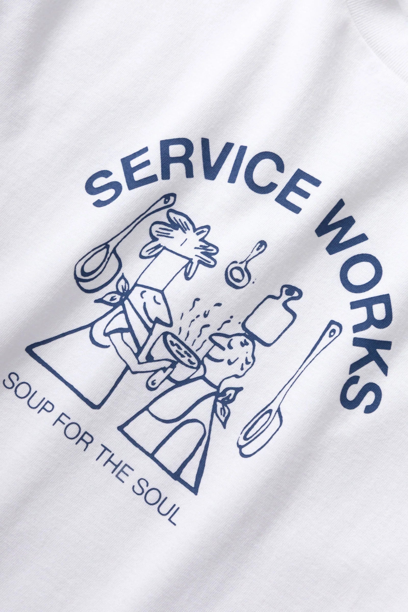 White t-shirt with blue graphic and text 'Service Works Soup for the Soul' on a white background