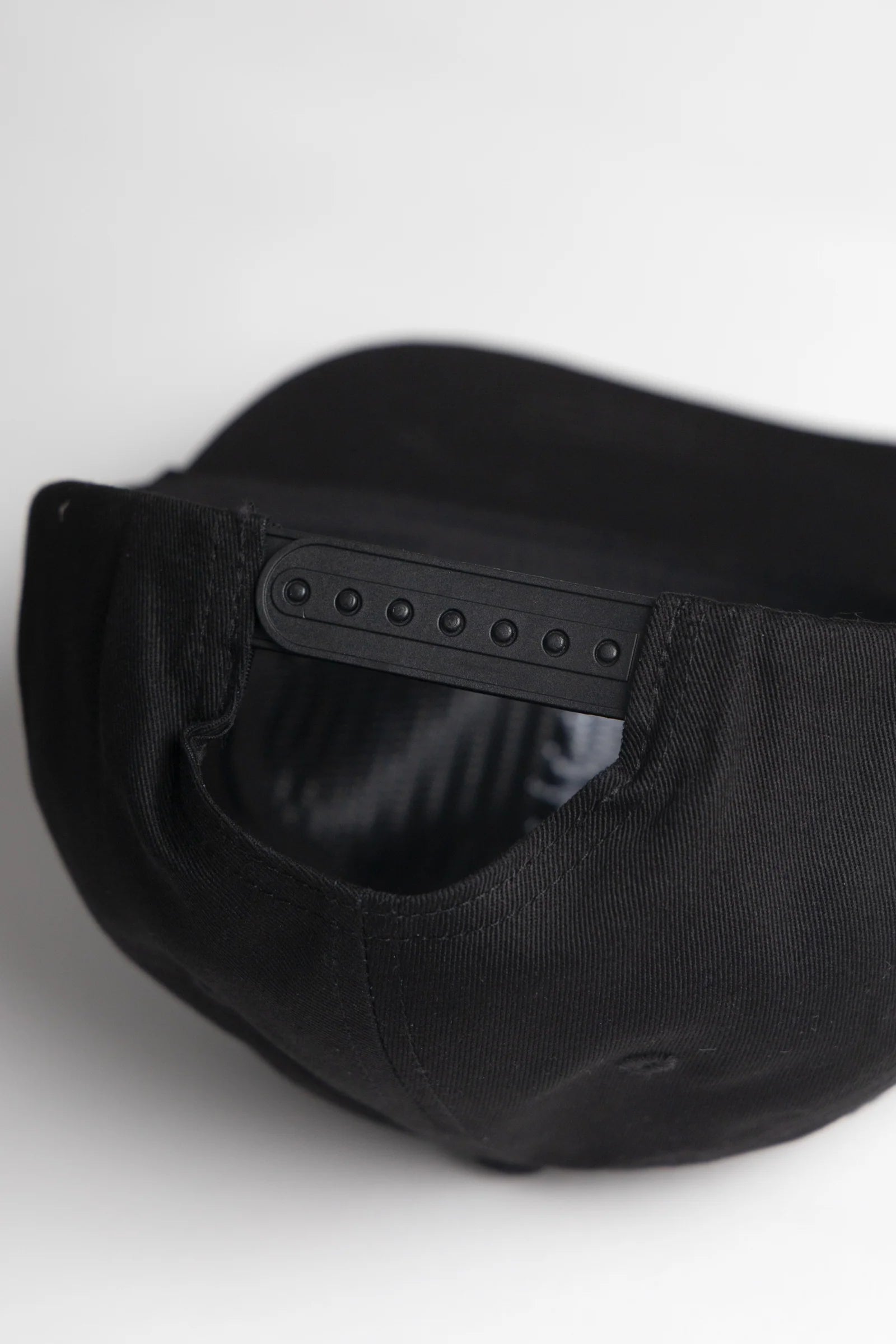 Black cap with a brand logo on the back against a white background