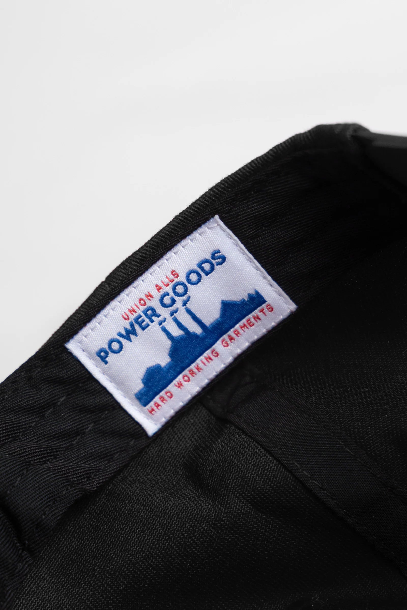 Close-up of a black garment with a visible label on a white background