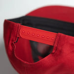 Close-up of a red cap with a black interior on a light gray background