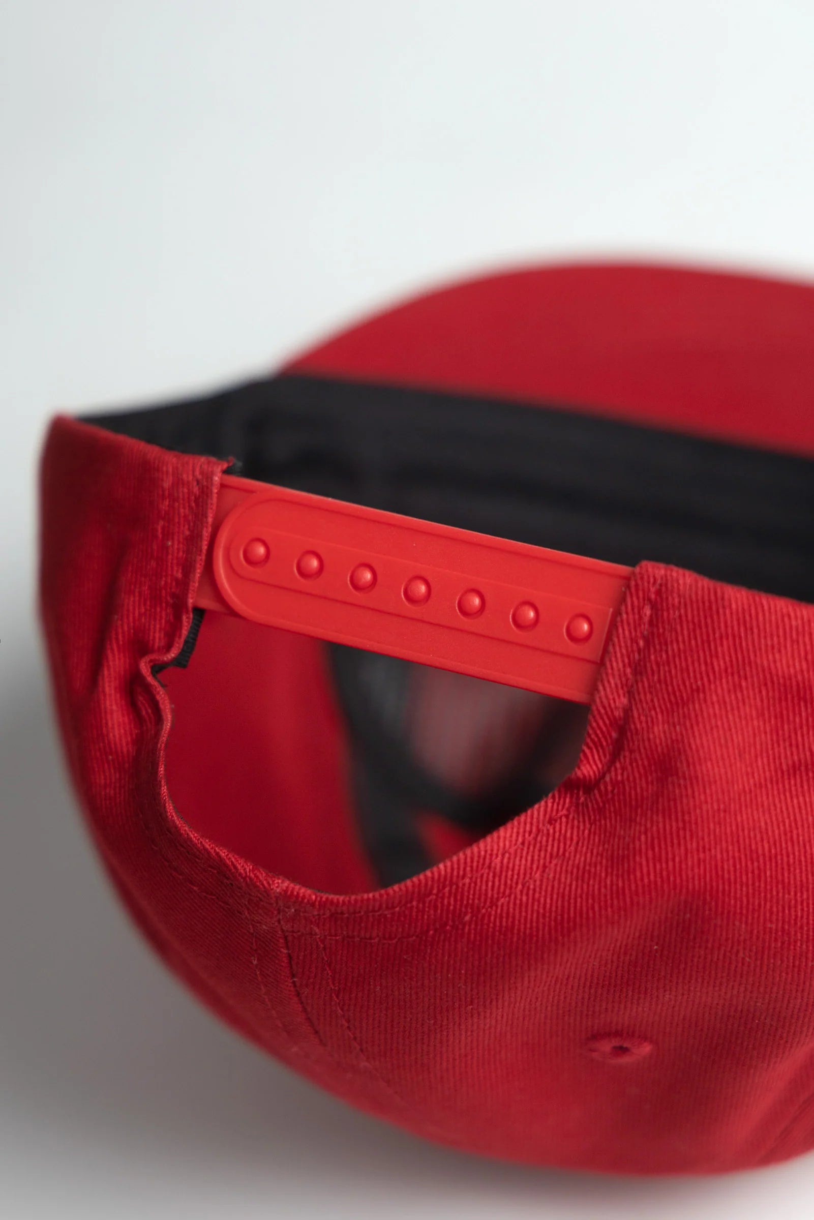 Close-up of a red cap with a black interior on a light gray background