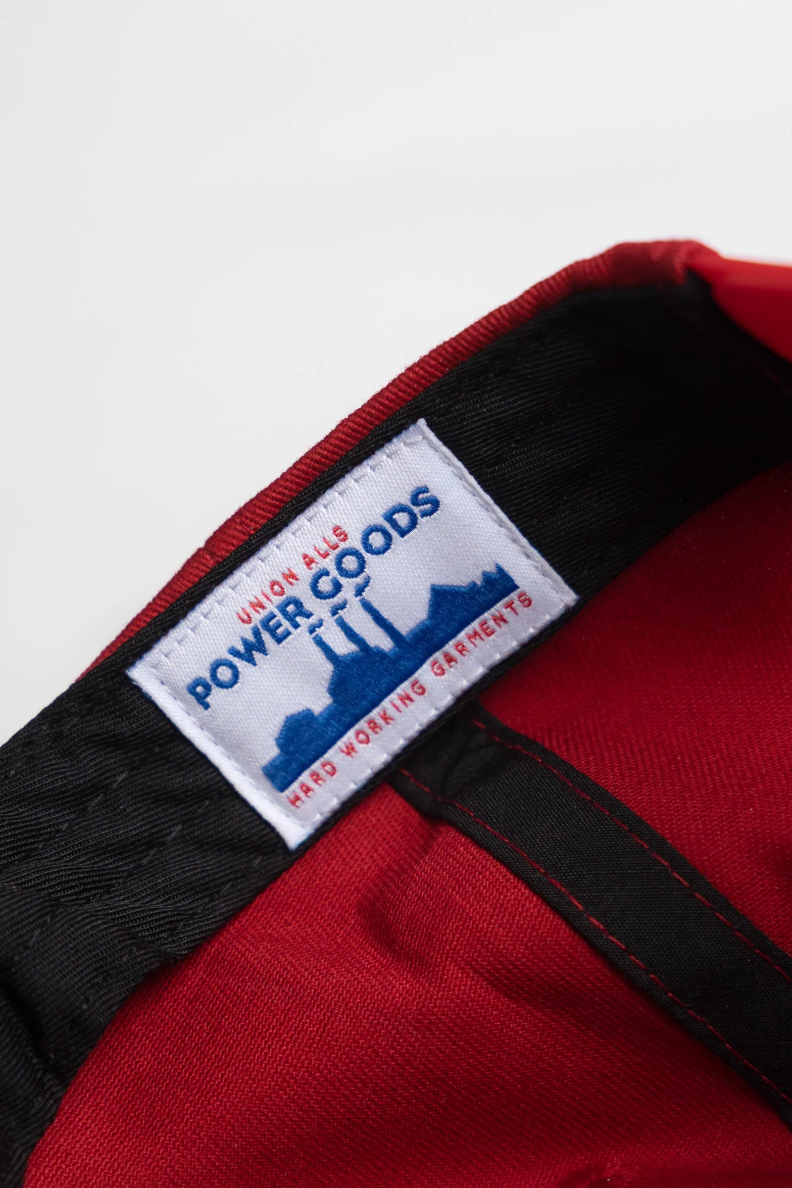 Close-up of a red jacket with a 'Power Goods' label on a white background
