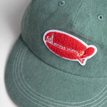 Green cap with a red and white logo on a light gray background