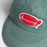 Green cap with a red and white logo on a light gray background