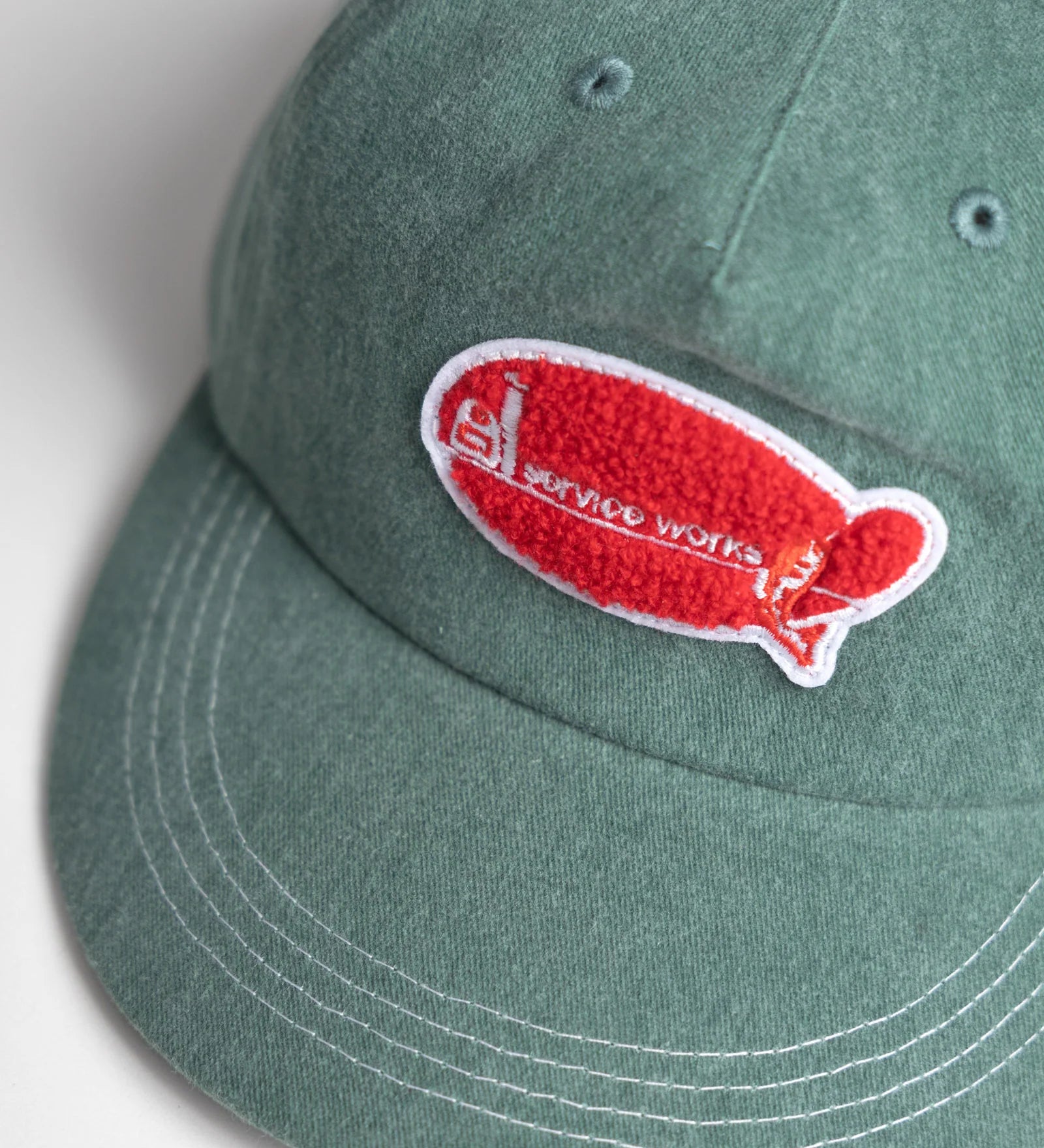 Green cap with a red and white logo on a light gray background