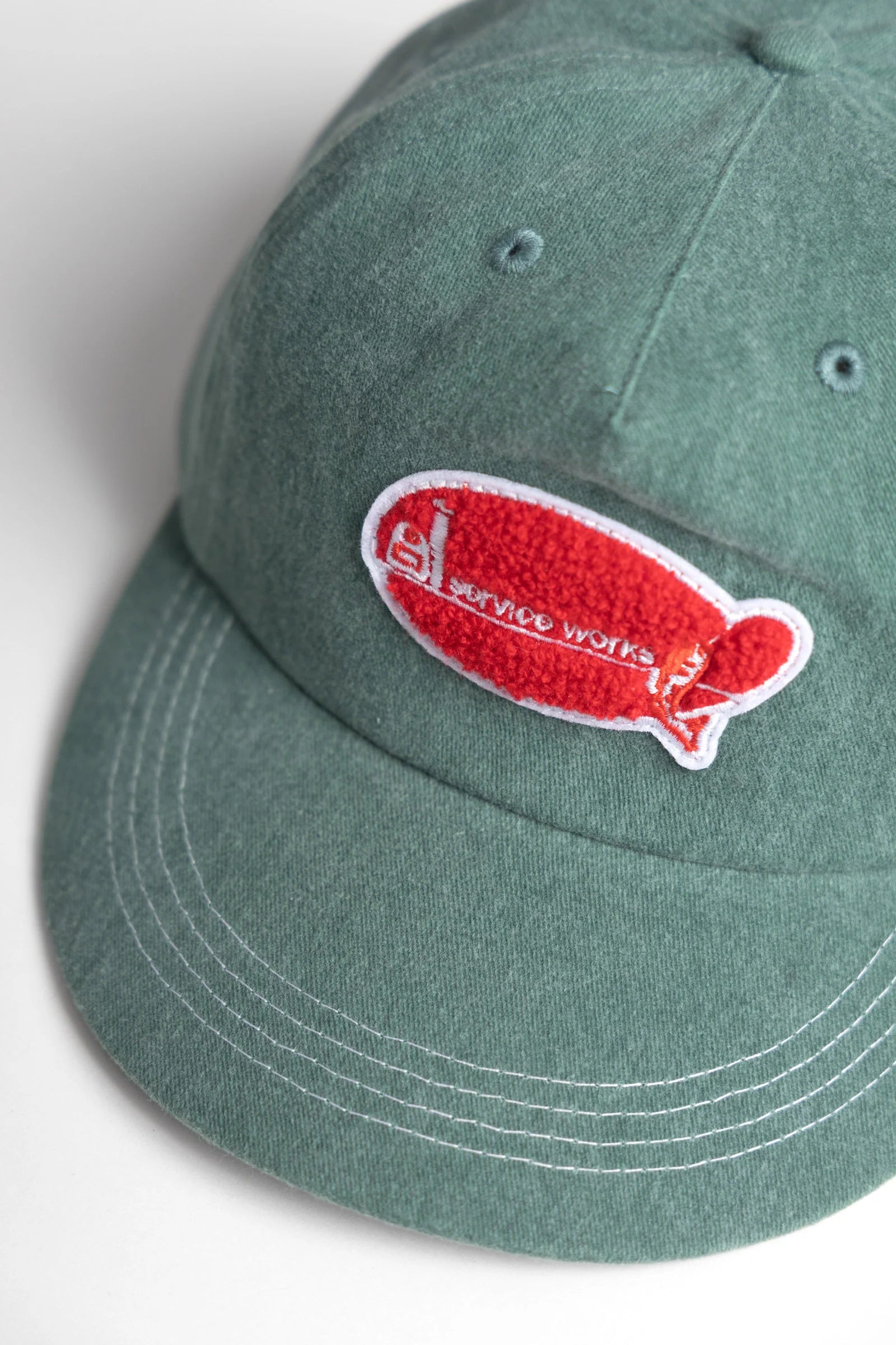 Green cap with a red and white logo on a light gray background