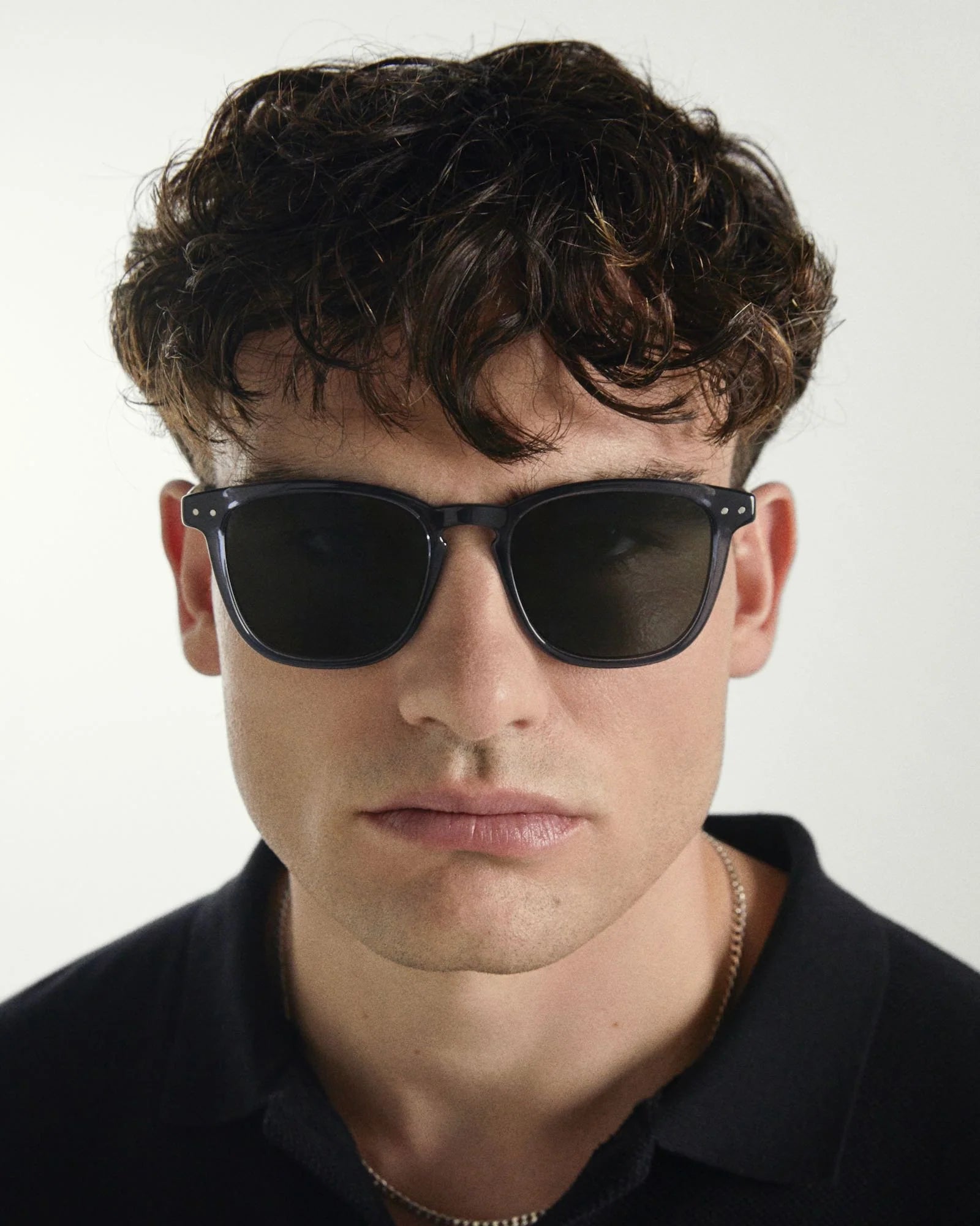Man wearing dark sunglasses with a neutral background
