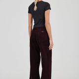 Woman wearing a black t-shirt and dark brown pants on a white background