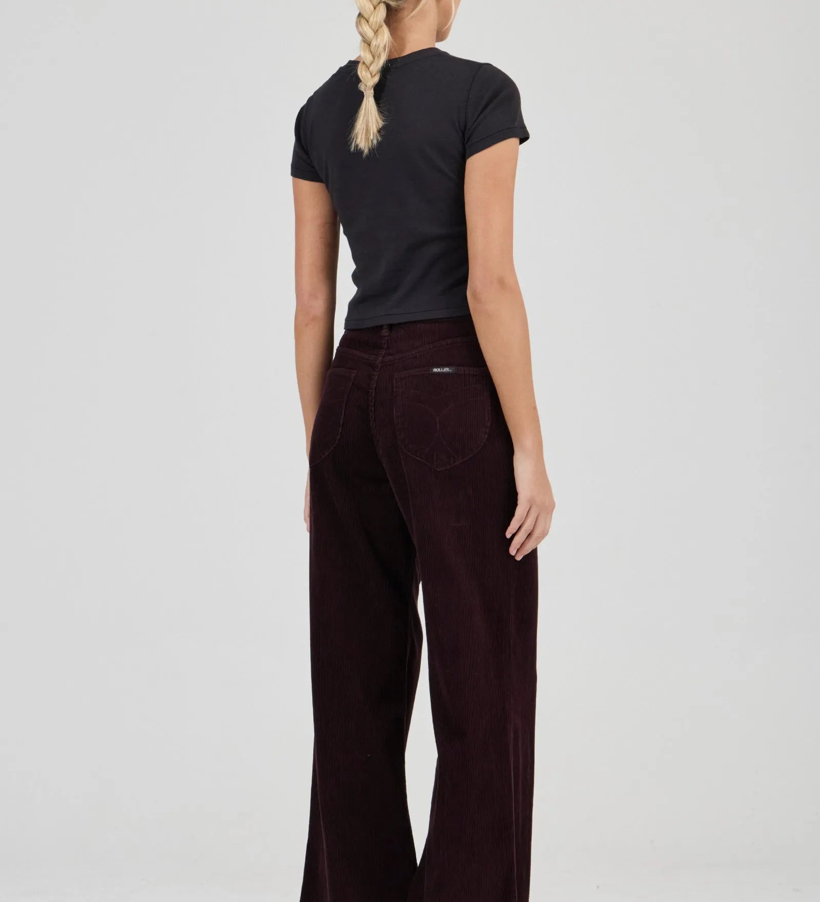 Woman wearing a black t-shirt and dark brown pants on a white background