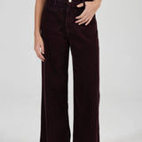 Person wearing dark brown wide-leg pants on a white background