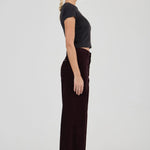 Woman wearing a black top and dark pants on a white background