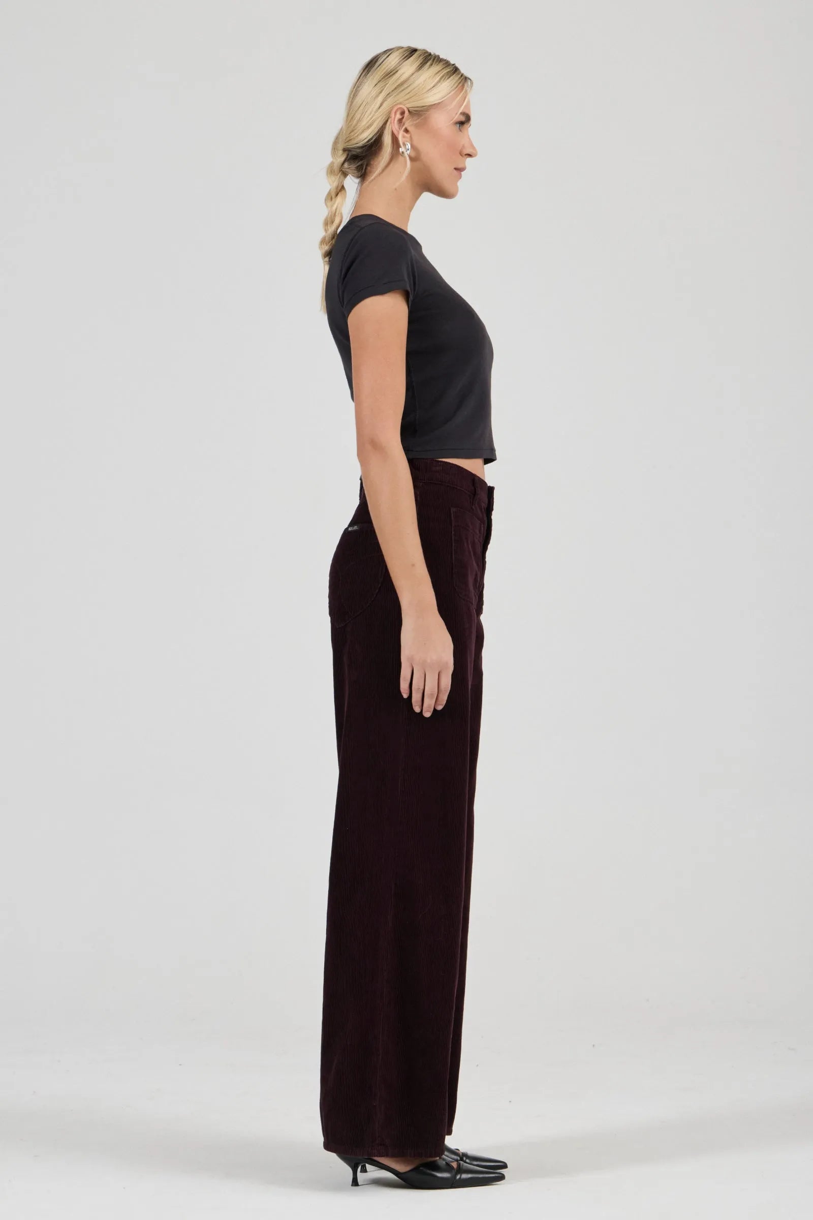 Woman wearing a black top and dark pants on a white background