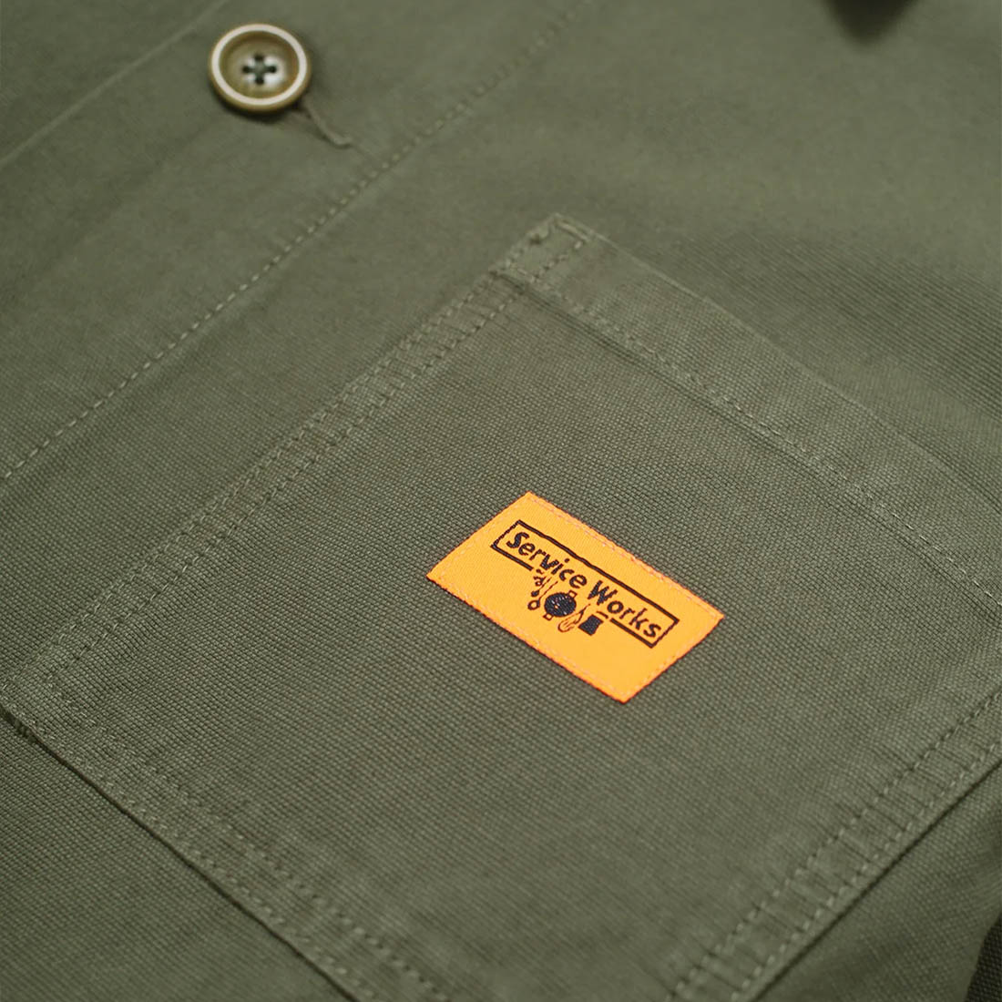 Close-up of a green fabric pocket with a visible brand label on a green background