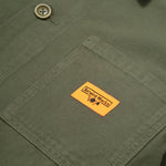 Close-up of a green fabric pocket with a visible brand label on a green background