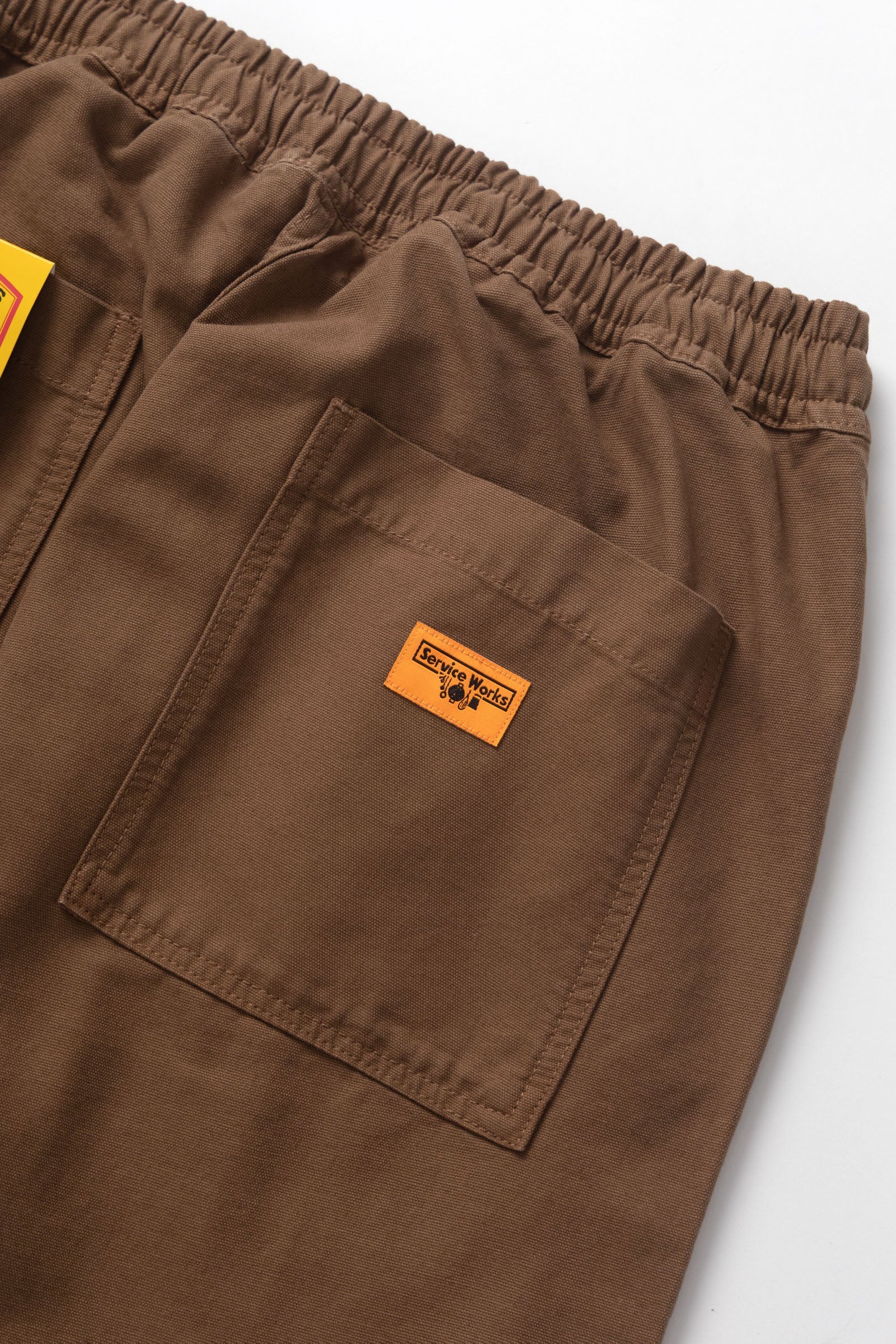 Brown pants with a logo patch on a white background