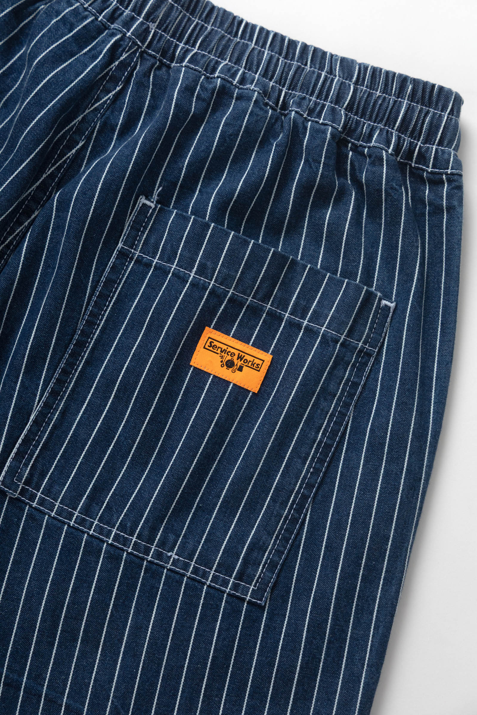 Close-up of blue pinstripe pants with an orange label on a white background