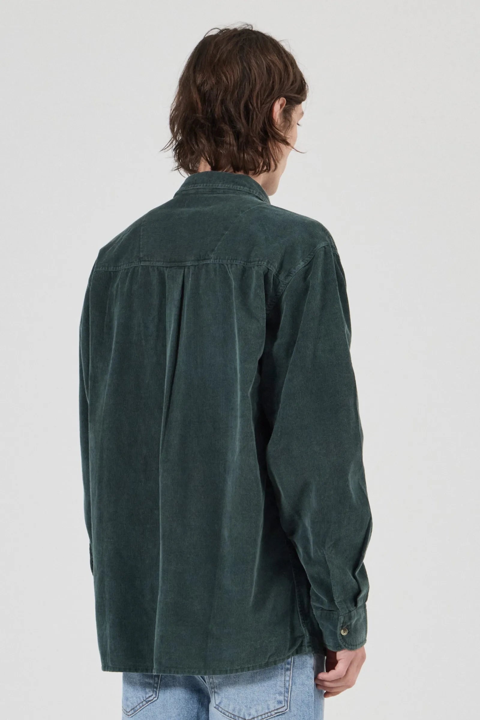 Person wearing a green shirt from behind on a white background