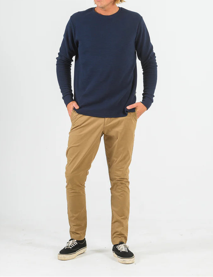 Person wearing a navy sweater and beige pants on a white background