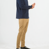 Man wearing a navy long-sleeve shirt and beige pants on a white background