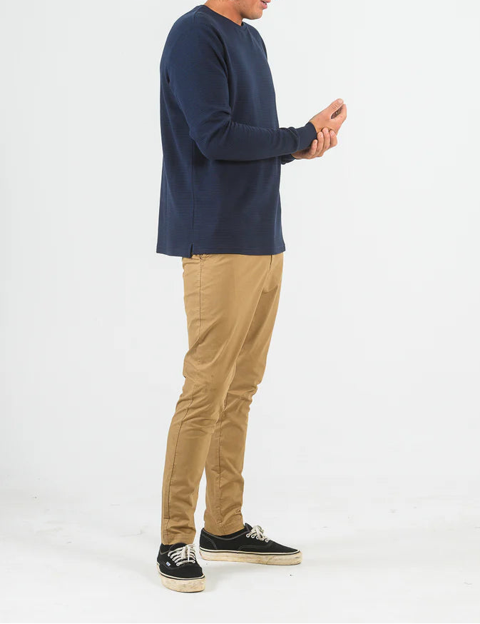 Man wearing a navy long-sleeve shirt and beige pants on a white background