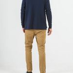 Person wearing a navy long-sleeve shirt and beige pants on a white background