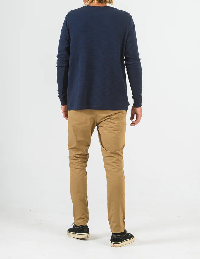 Person wearing a navy long-sleeve shirt and beige pants on a white background