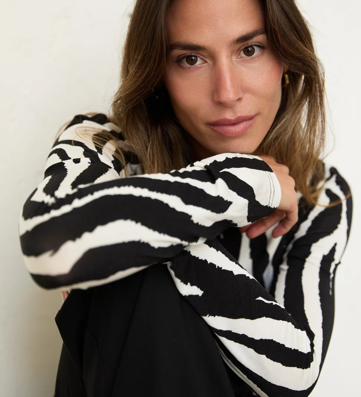 Woman wearing a black and white patterned sweater against a neutral background