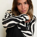 Woman wearing a black and white patterned sweater against a neutral background