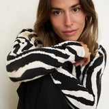 Woman wearing a black and white patterned sweater against a neutral background
