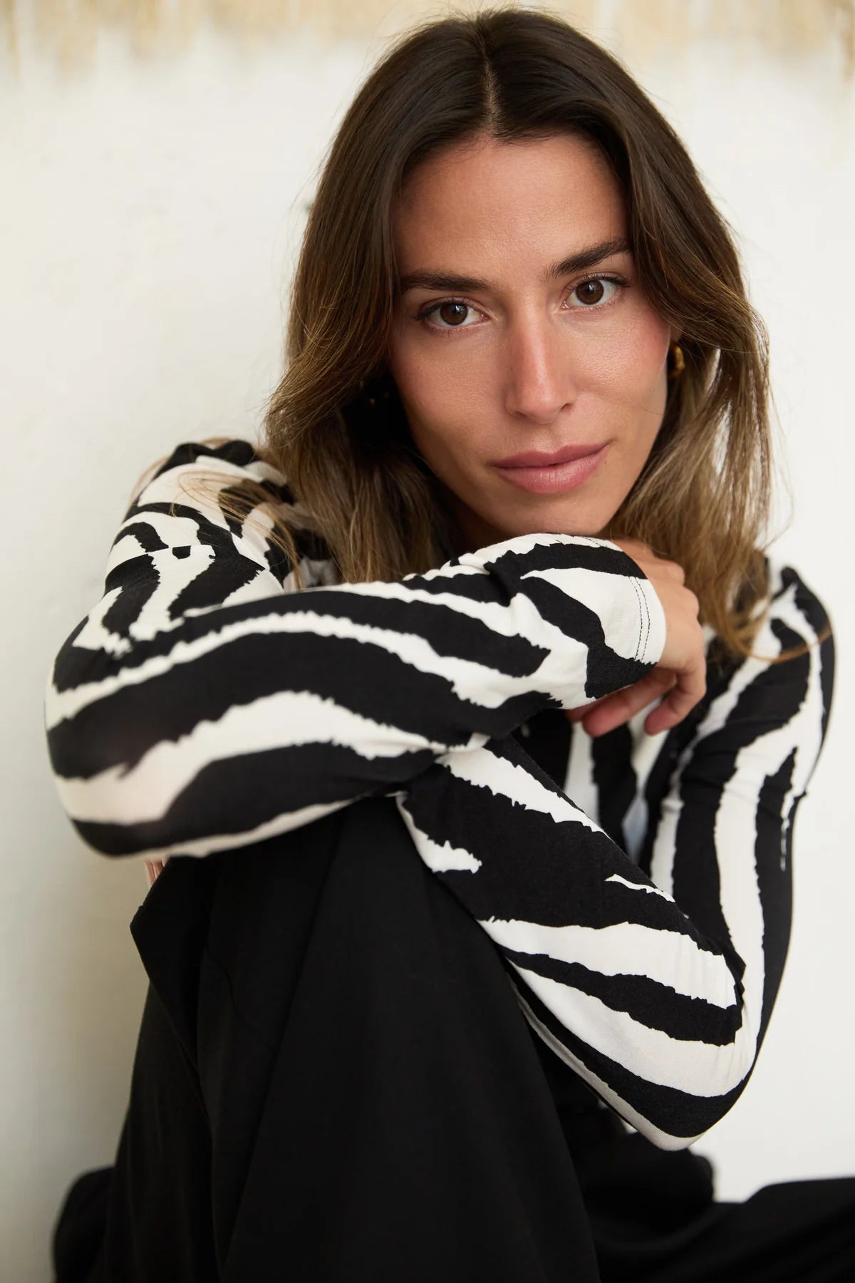 Woman wearing a black and white patterned sweater against a neutral background