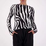 Person wearing a black and white zebra pattern sweater with black pants on a white background