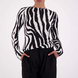 Person wearing a black and white zebra pattern sweater with black pants on a white background