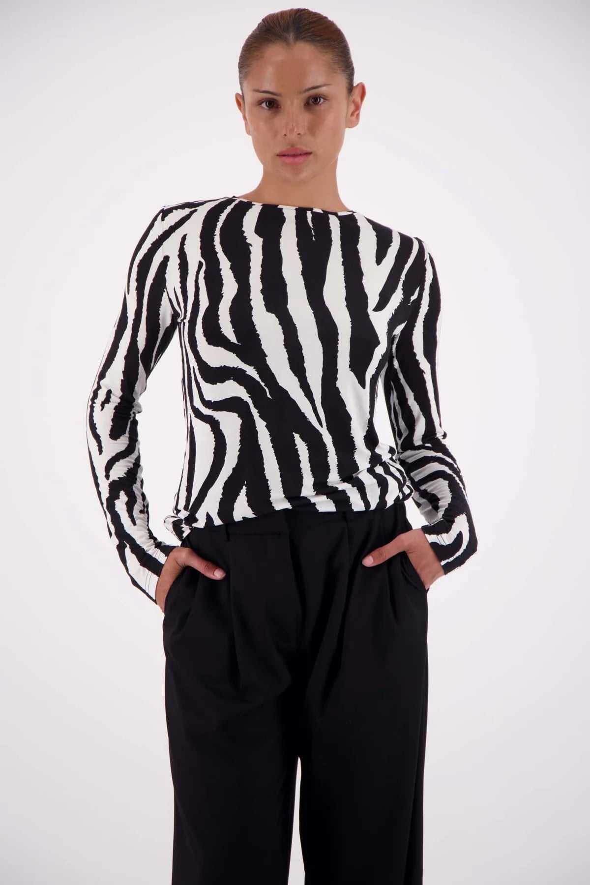 Person wearing a black and white zebra pattern sweater with black pants on a white background