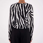 Person wearing a black and white zebra-striped sweater against a white background