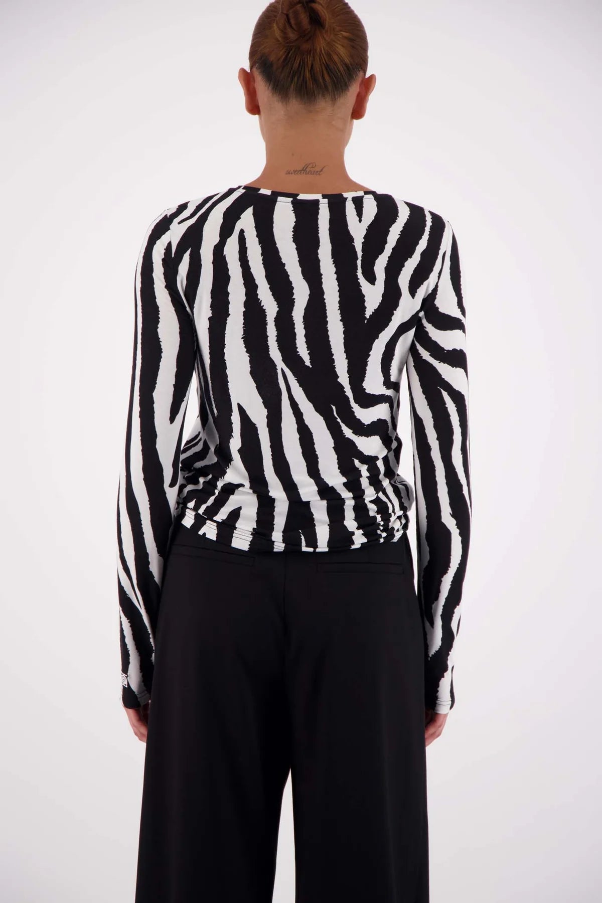 Person wearing a black and white zebra-striped sweater against a white background