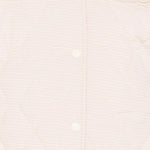 Close-up of a person wearing a light-colored shirt with a plain background