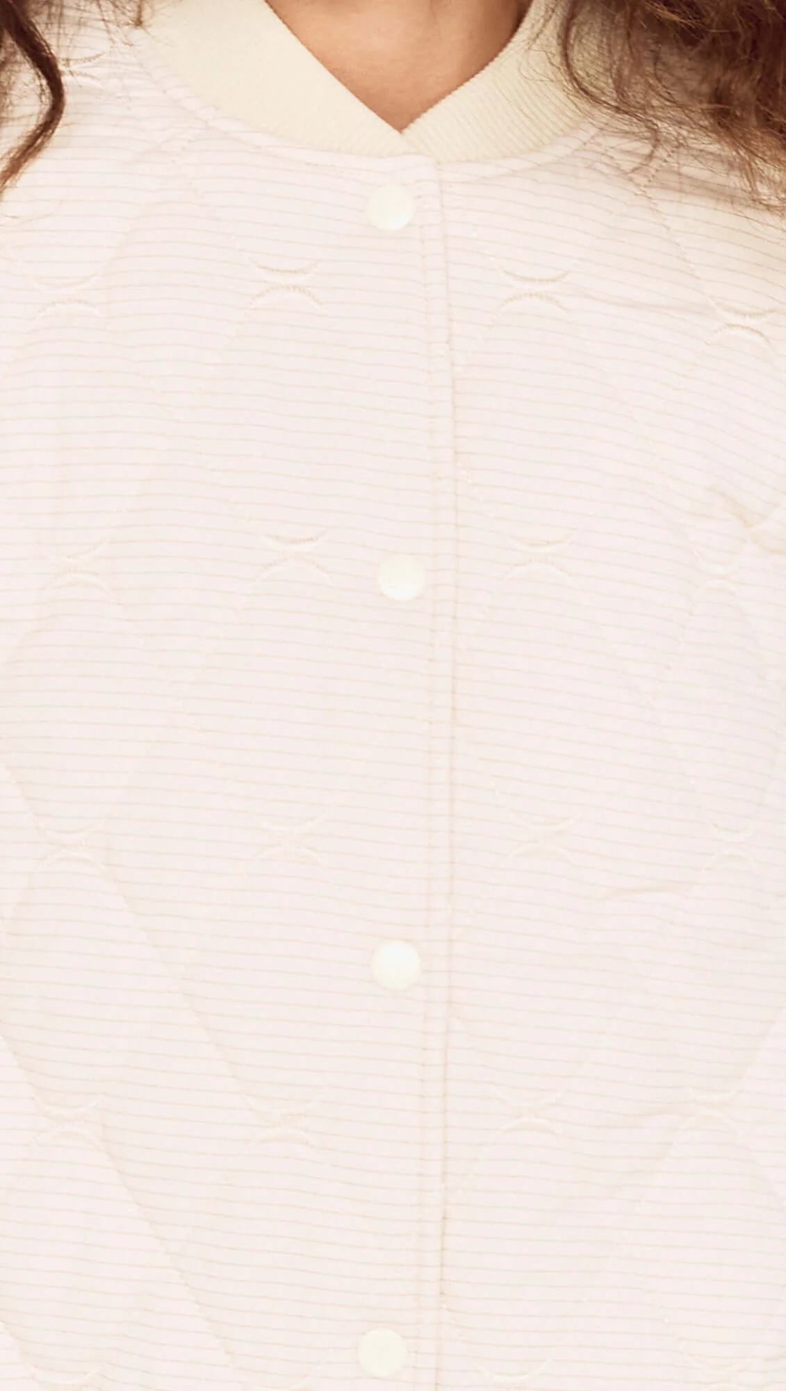 Close-up of a person wearing a light-colored shirt with a plain background