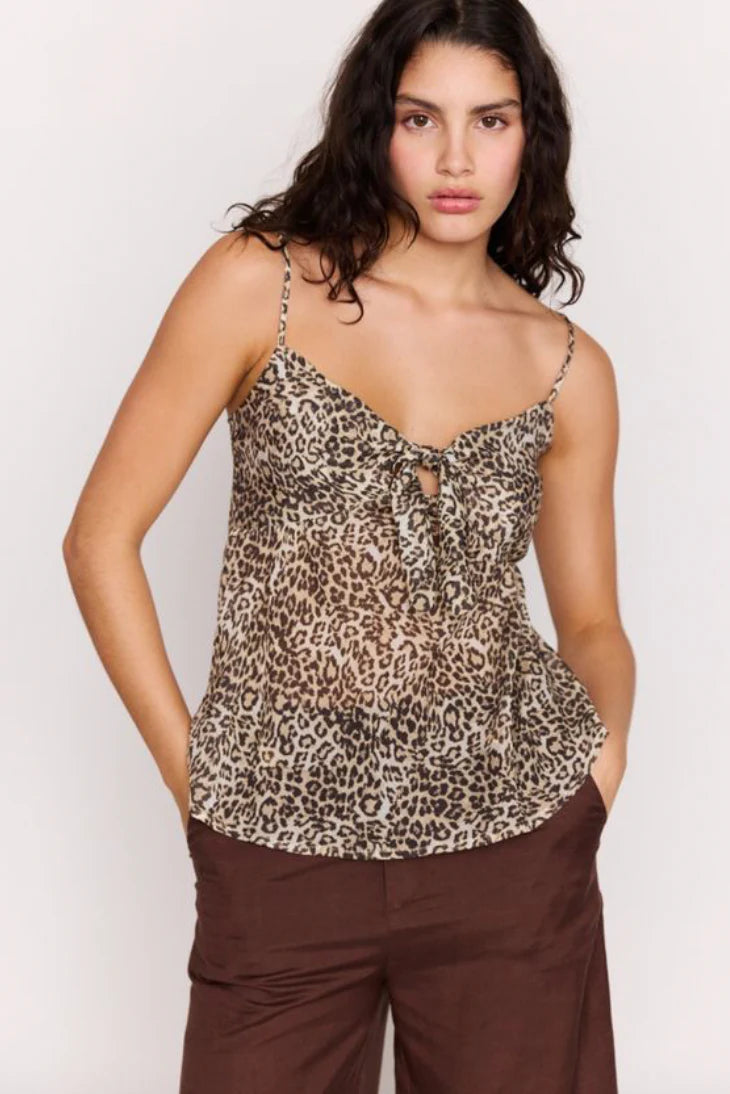 Woman wearing a leopard print top and brown pants on a white background